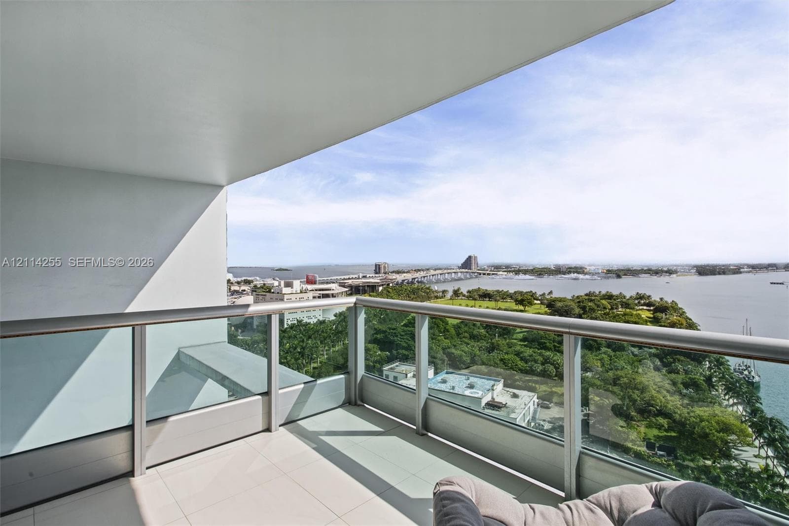 Covered balcony featuring tile flooring and a glass-paneled metal railing