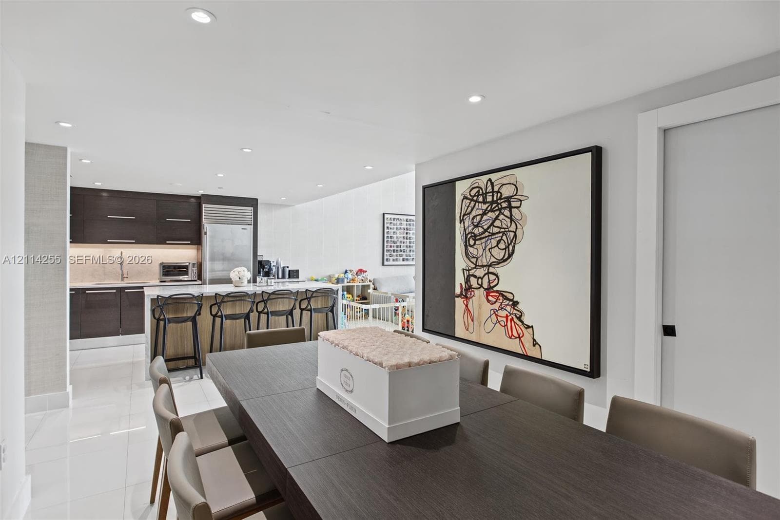 Open-concept kitchen featuring high-gloss dark cabinetry, integrated refrigerator, stone countertops, and recessed lighting throughout