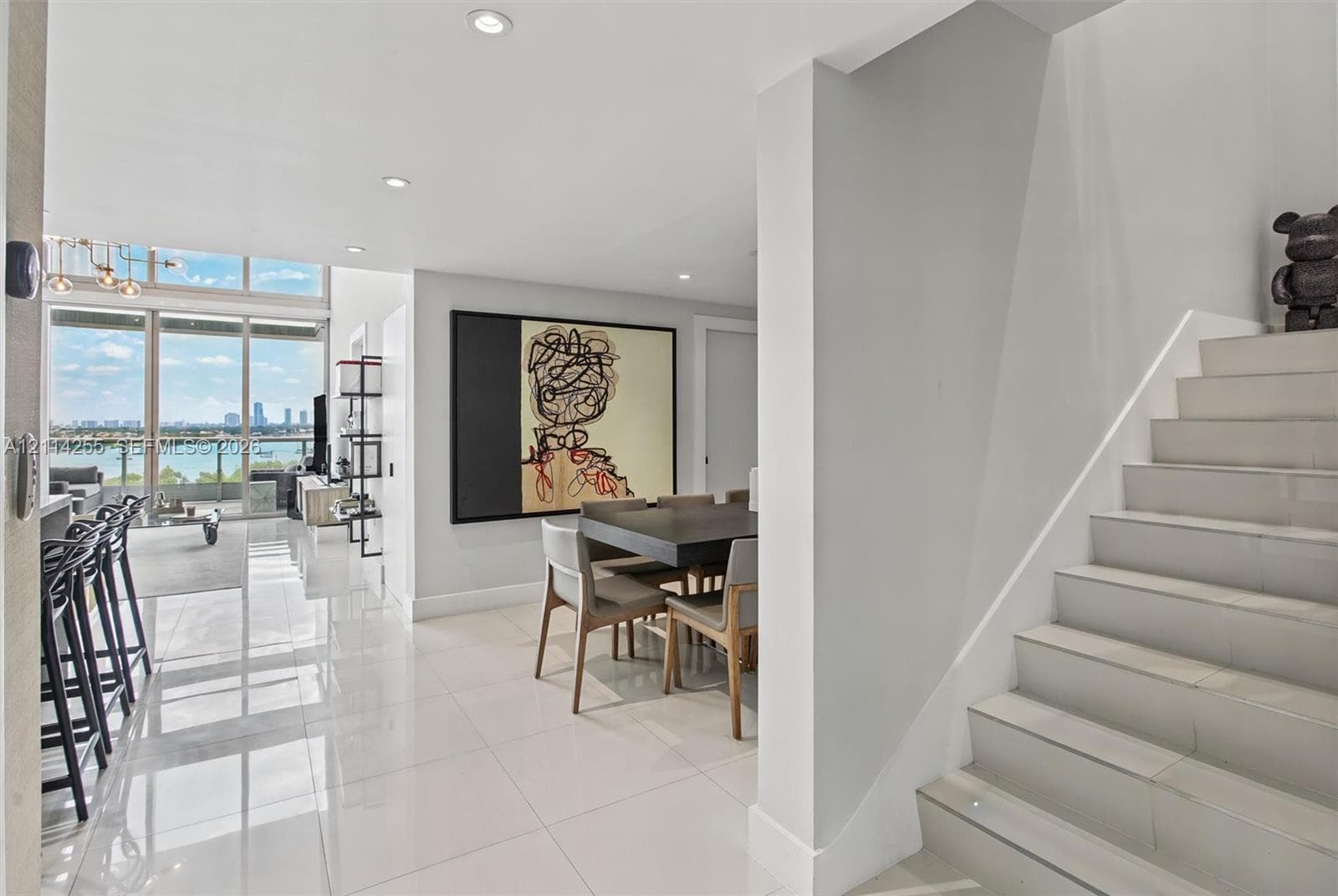 Polished tile flooring, floor-to-ceiling windows with water scenery, recessed lighting, and a staircase with tile treads