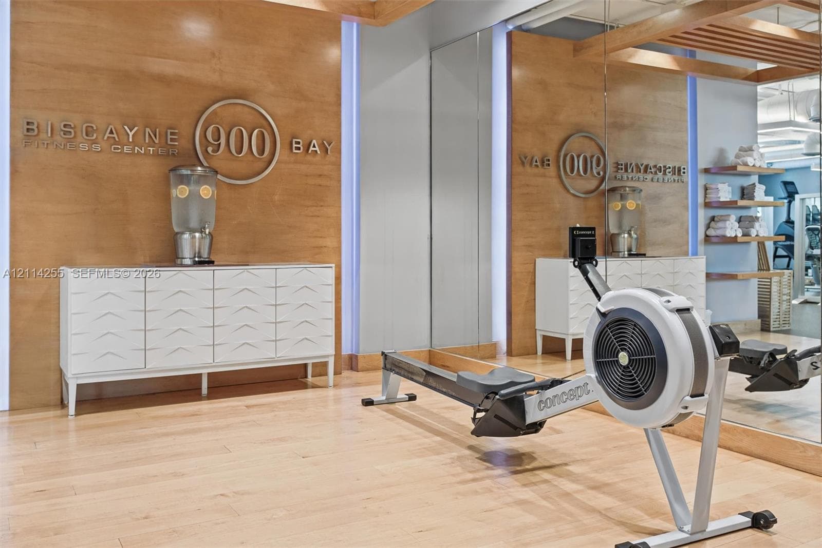 Fitness center featuring wood-panel wall accents, full-height wall mirrors, built-in recessed shelving, and wood-finish flooring