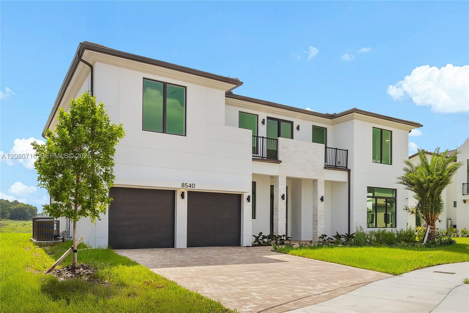 Modern exterior architecture with a white facade, black-framed windows, and a paver driveway