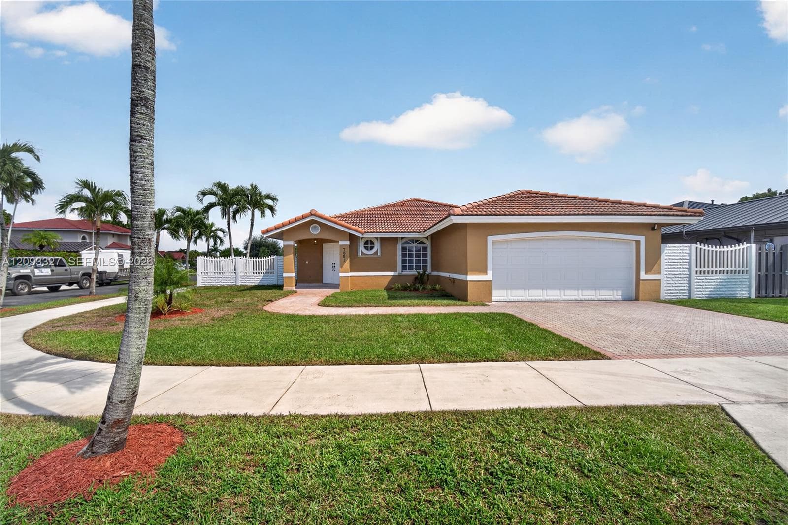 Single-story residence featuring a clay tile roof, stucco exterior, paved driveway, two-car garage, and a brick-paver walkway