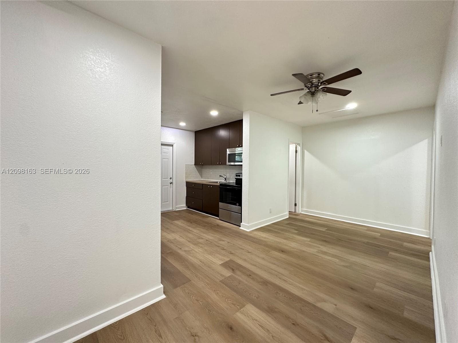Interior space featuring wood-finish flooring, dark cabinetry, recessed lighting, and a ceiling fan with light fixture