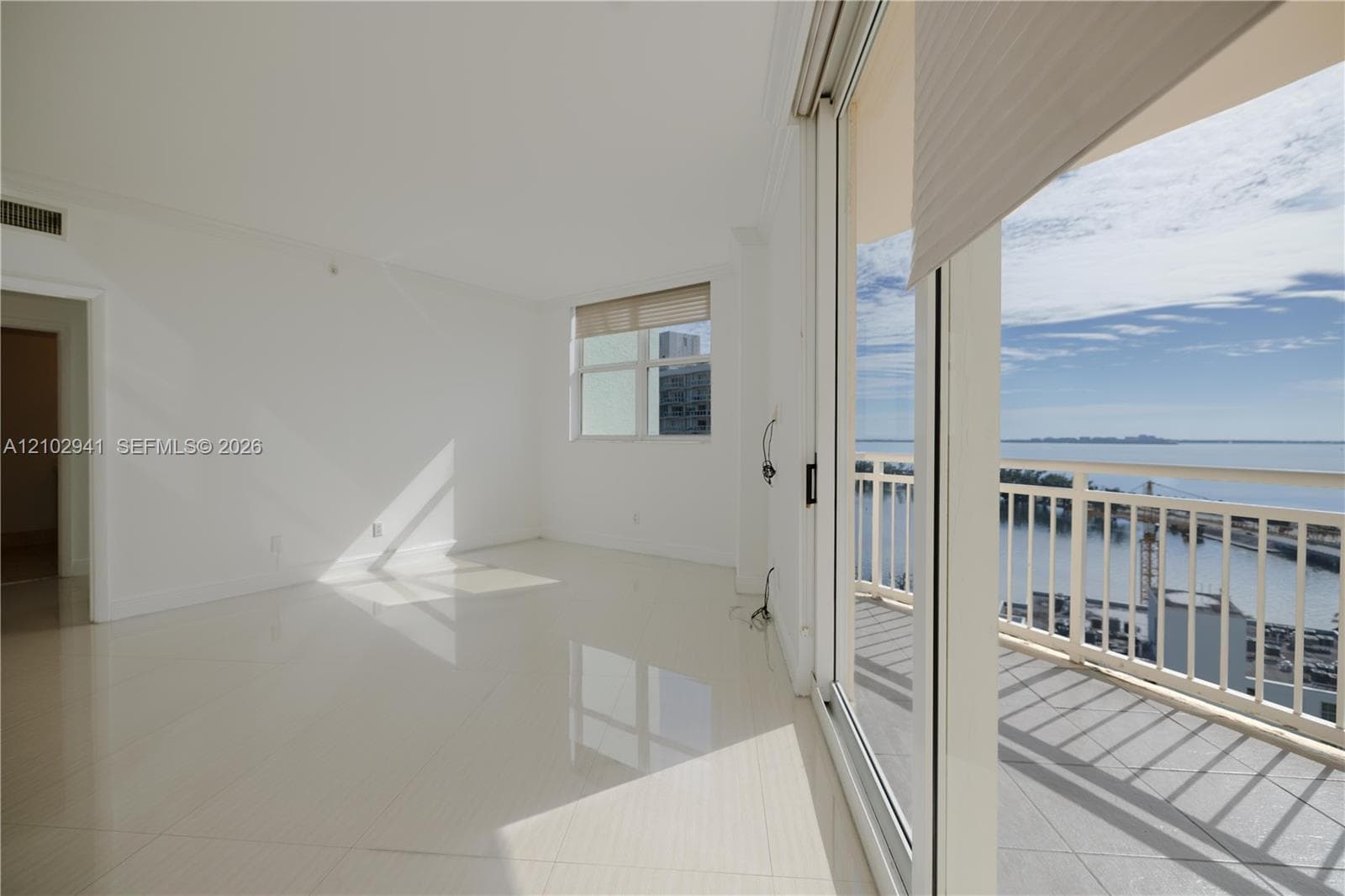 Interior space featuring polished tile flooring, full-height sliding glass doors, and a private balcony with metal railing