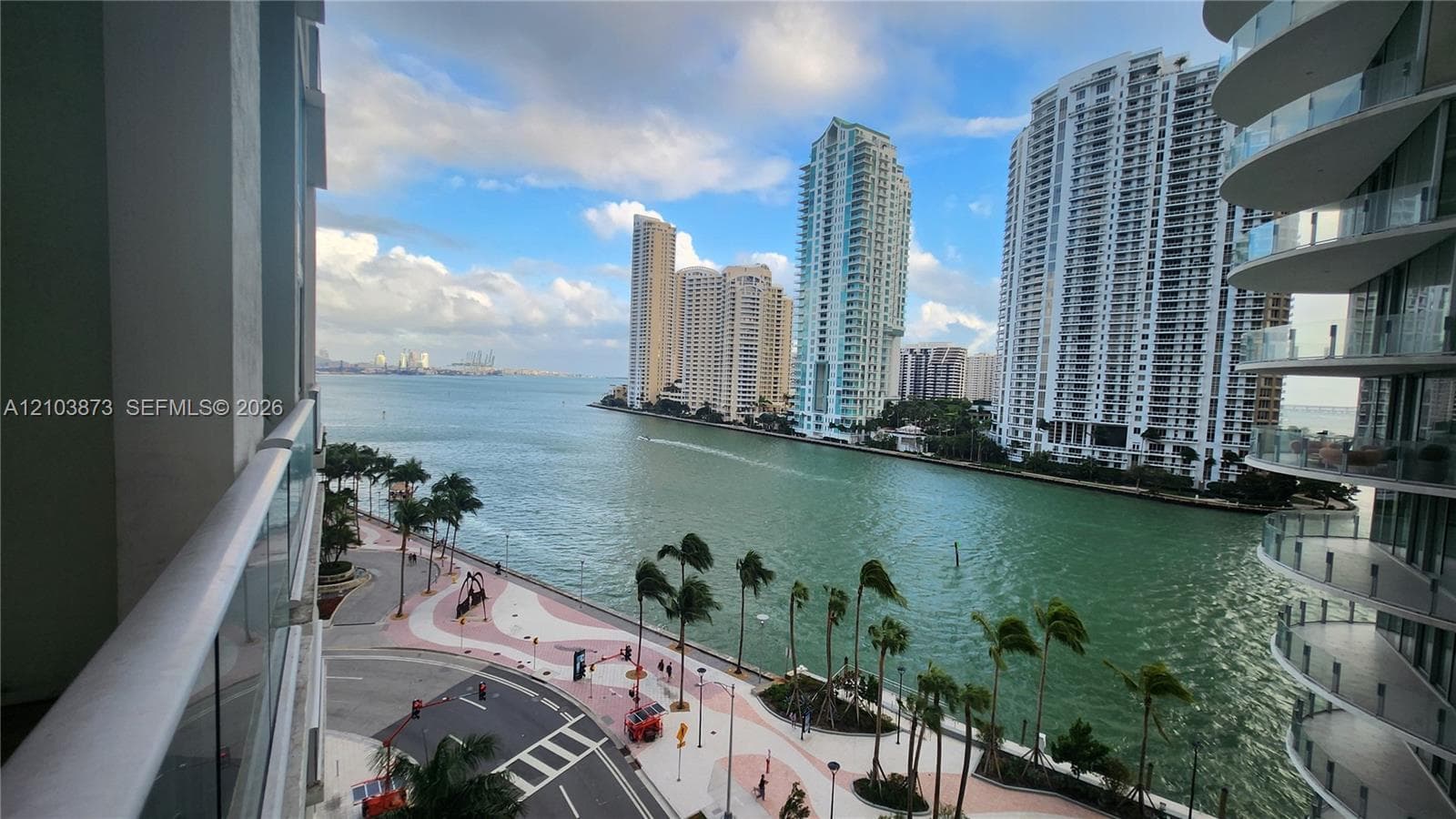 Elevated balcony featuring a glass-panel railing and panoramic waterfront scenery encompassing the harbor and urban skyline