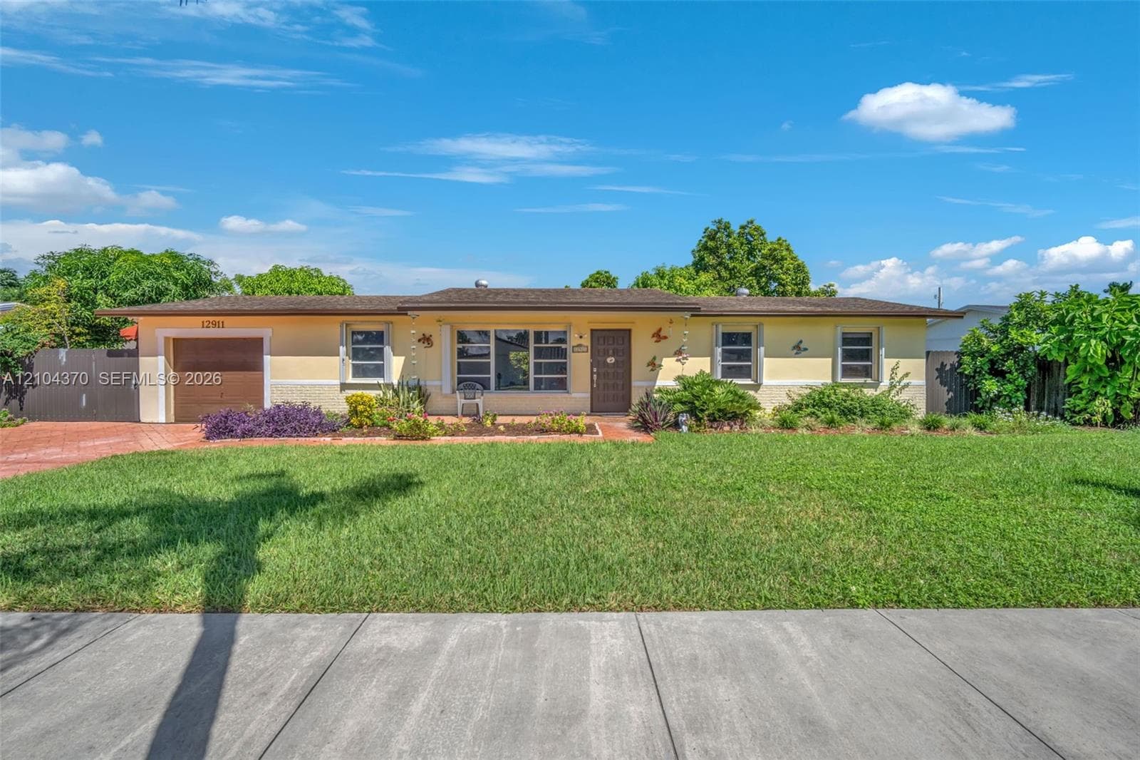 Single-story residence featuring a shingled roof, stucco exterior, attached garage, and a paved driveway, situated on a lot with mature landscaping
