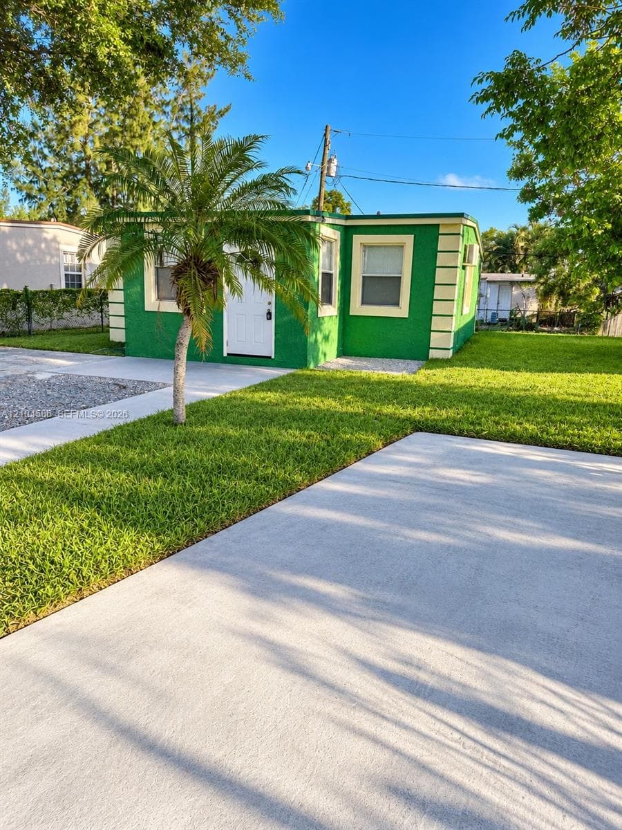 Exterior featuring smooth stucco walls with decorative corner quoins, concrete driveway, and manicured lawn