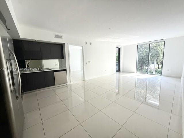Large-format tile flooring, flat-panel dark cabinetry, stainless steel appliances, and floor-to-ceiling glass sliding doors