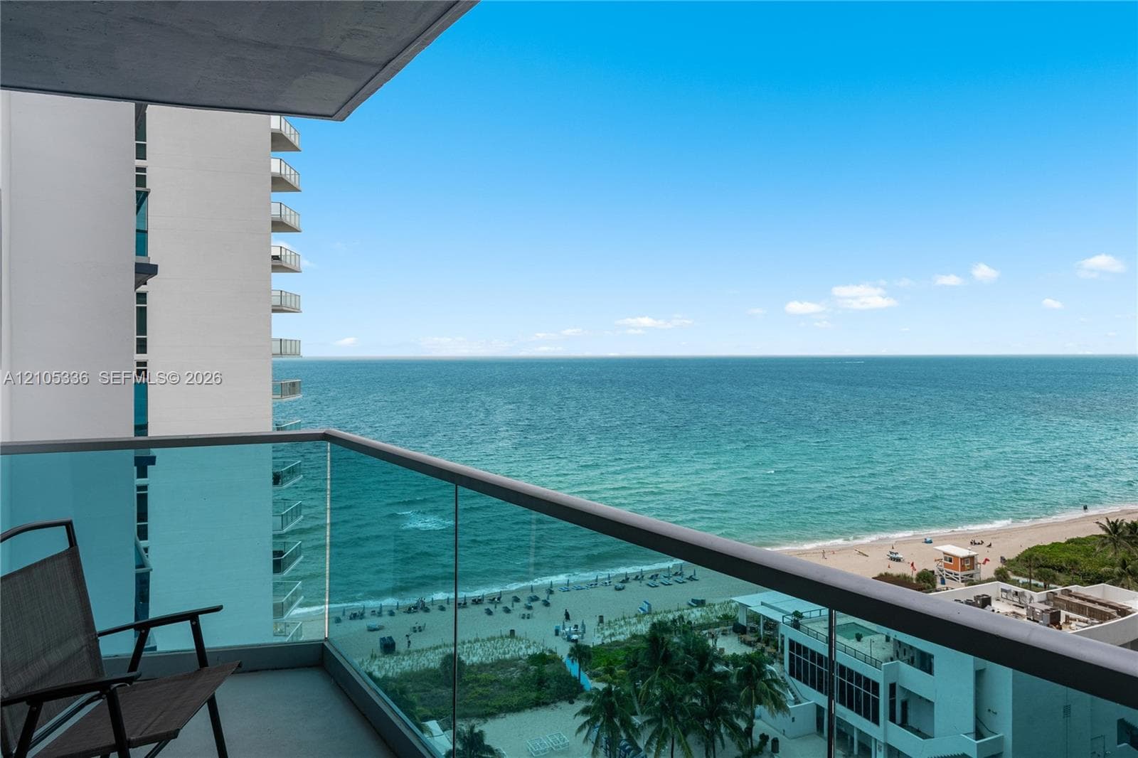 Private balcony featuring glass panel railing and ocean scenery