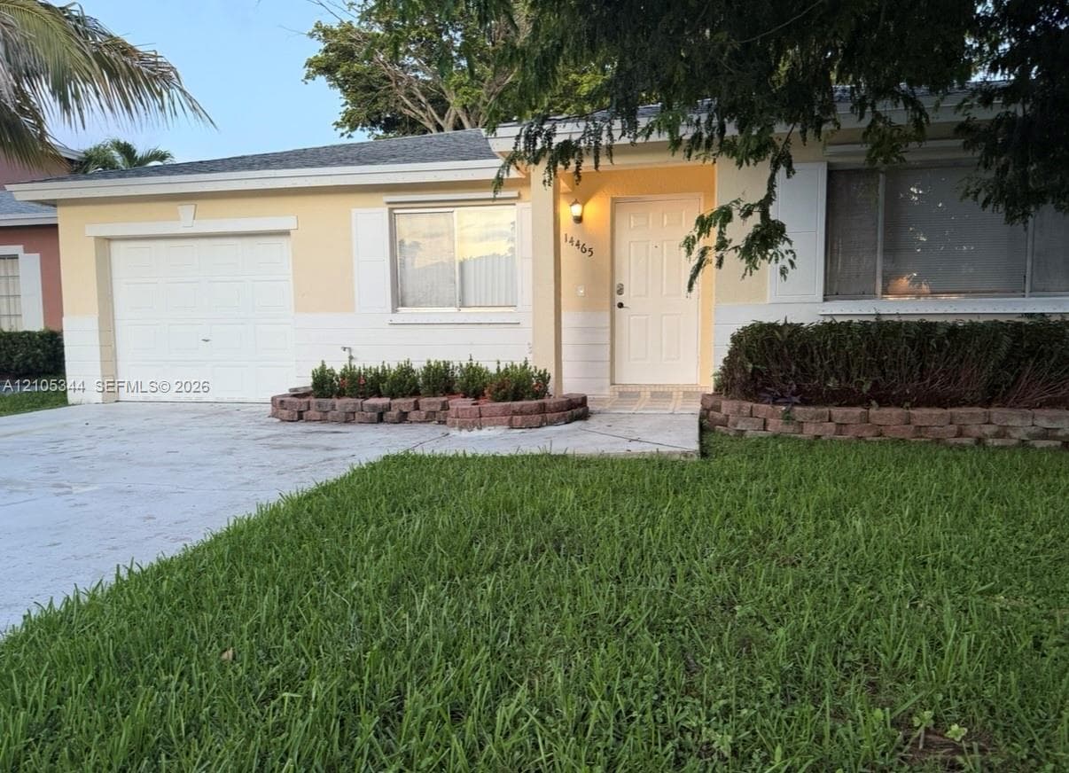 Single-story property with a light-colored stucco exterior, attached garage, and a concrete driveway