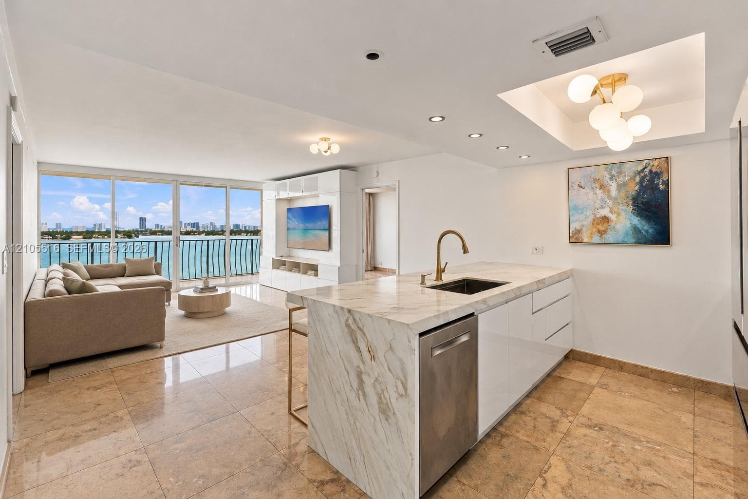 Open-concept living space featuring expansive glass doors, water scenery, stone flooring, a waterfall island, and built-in shelving