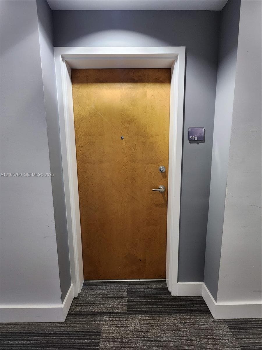 Solid-core wood-finish door with brushed metallic hardware, integrated security peephole, and white architectural casing