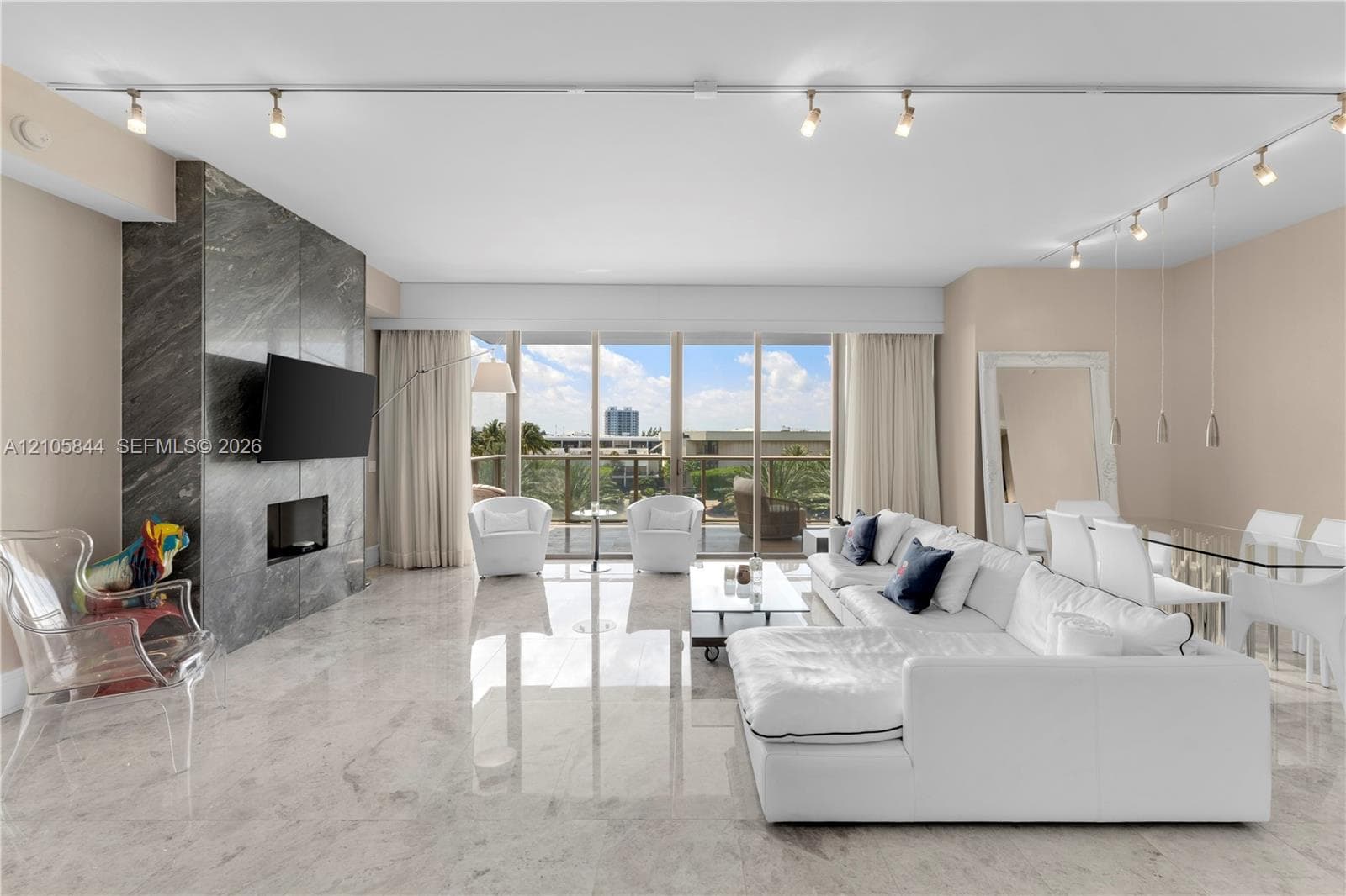 Polished stone flooring, floor-to-ceiling windows, stone-clad fireplace surround, and recessed track lighting