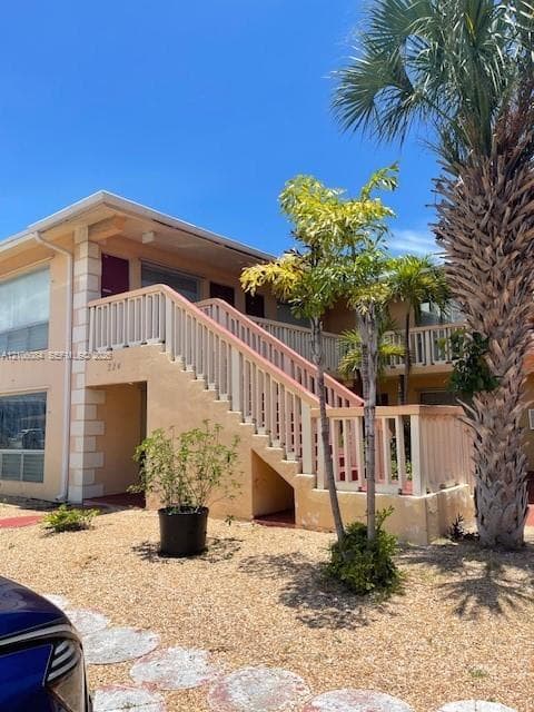 Stucco exterior with multi-level wood railing staircase providing direct access to upper and lower decks
