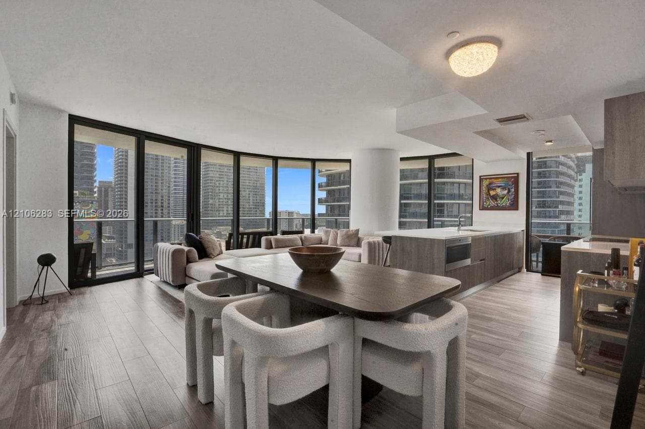Open-concept living space featuring floor-to-ceiling windows, wood-finish flooring, a kitchen island with stone countertops, and recessed lighting