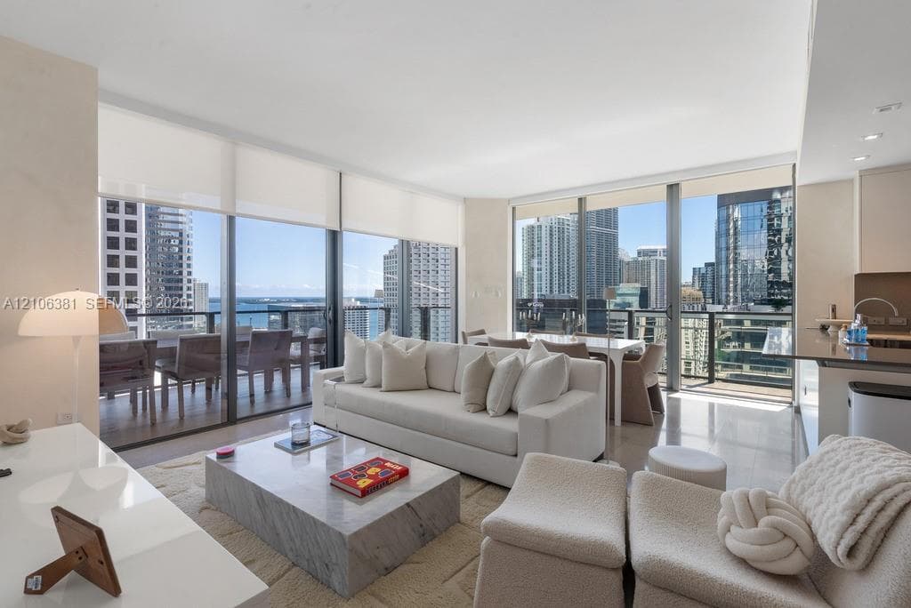 Living area featuring floor-to-ceiling glass windows, recessed lighting, polished stone flooring, and a private balcony
