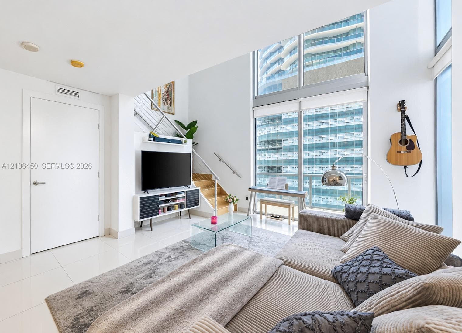 Living area featuring floor-to-ceiling windows, porcelain tile flooring, and a staircase with metal railings