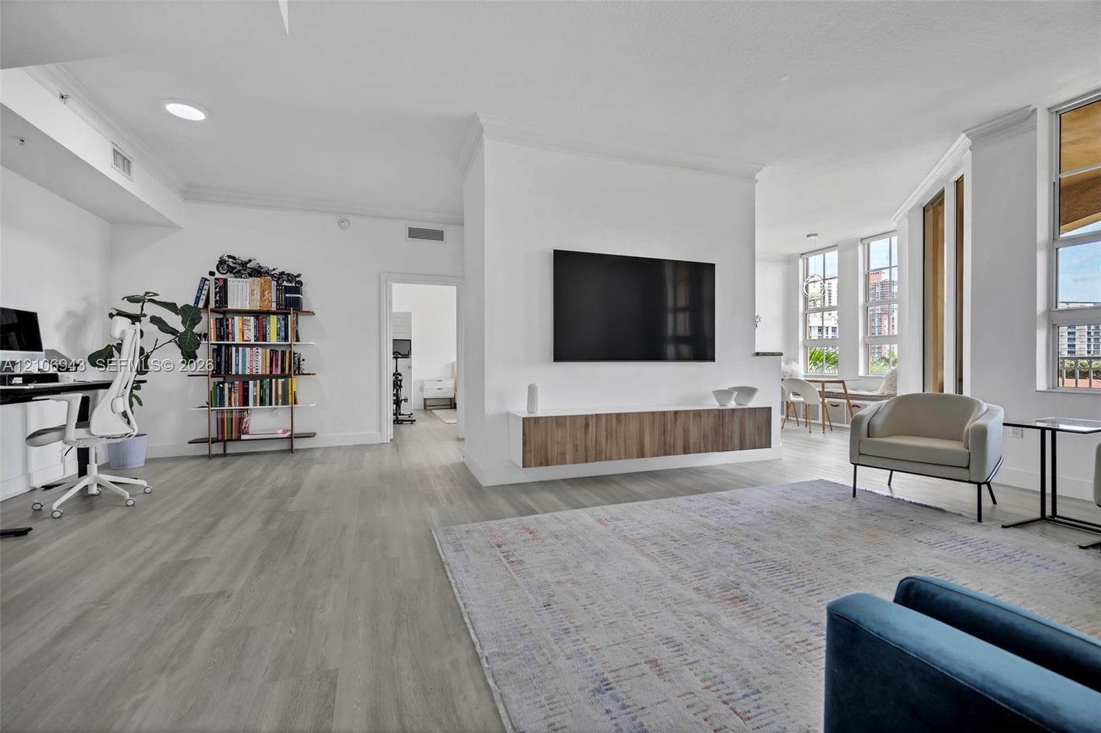 Open-concept room featuring wood-finish flooring, a wall-mounted floating media console, recessed lighting, and expansive windows