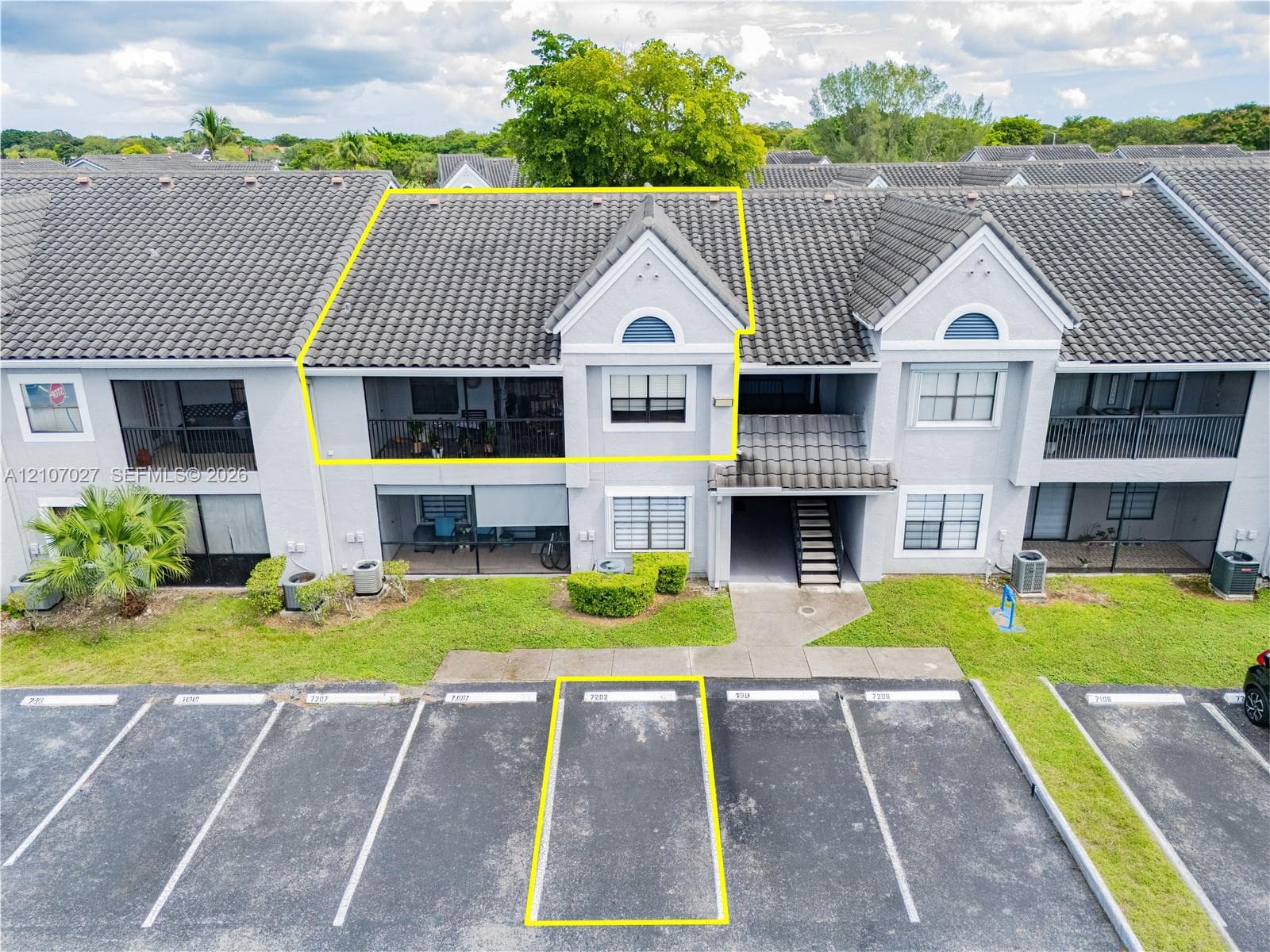 Multi-story residence featuring a tile roof, private balcony, stucco exterior, and dedicated surface parking space