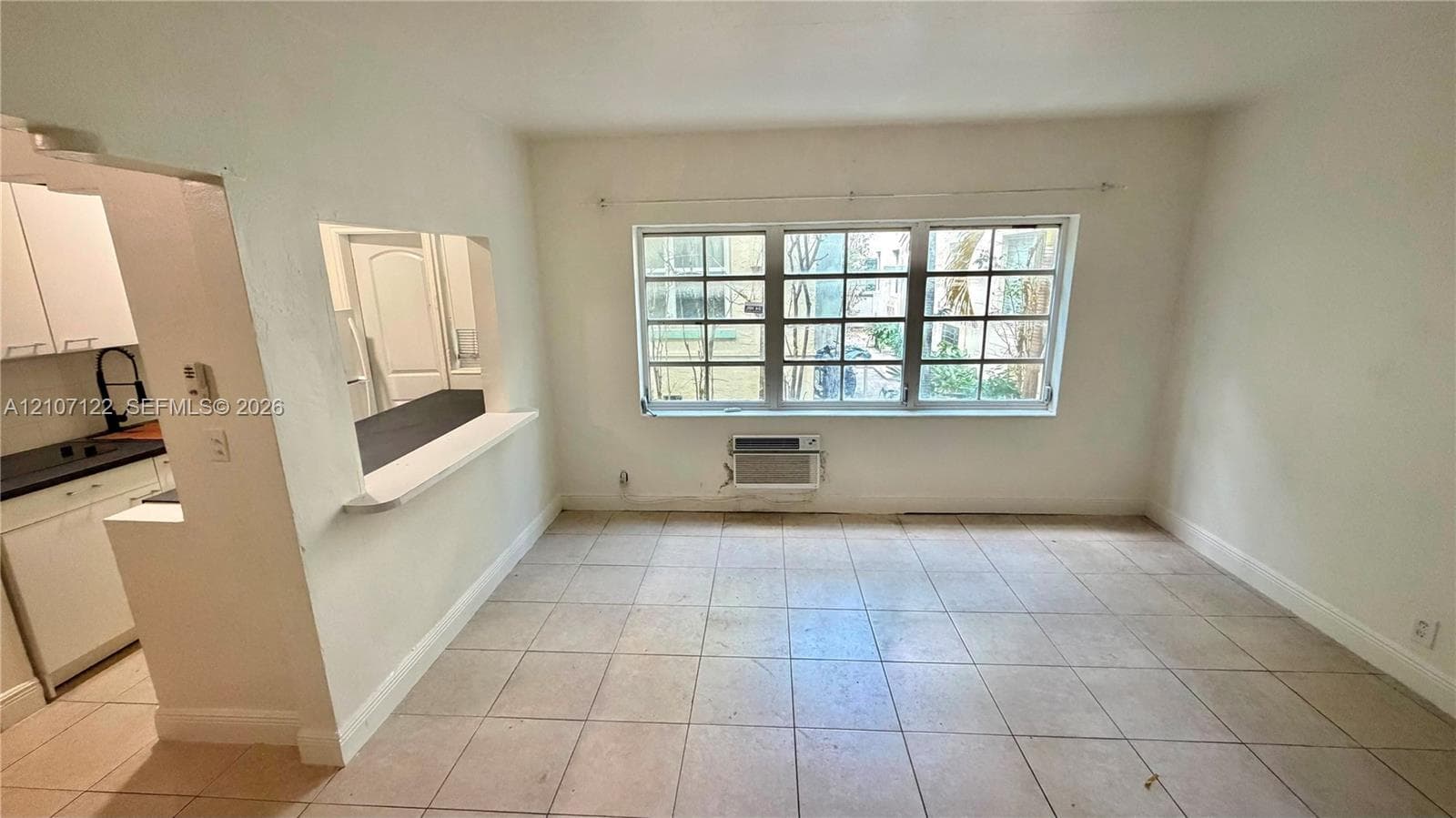 Neutral-toned tile flooring, large multi-pane windows, and a pass-through opening with a built-in counter