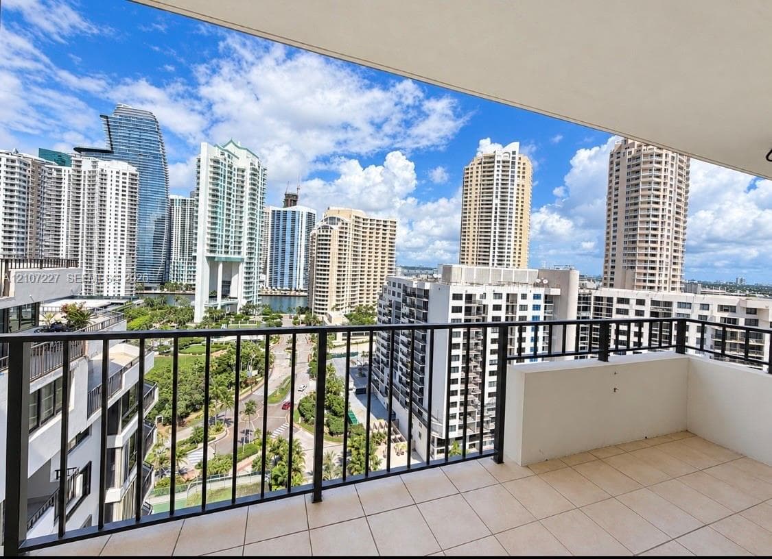 Covered balcony featuring tile flooring and a black metal railing, showcasing an expansive cityscape