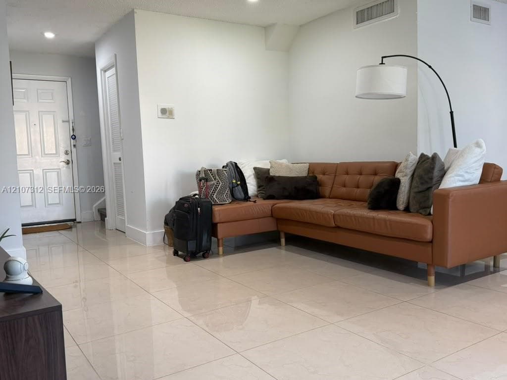 Large-format tile flooring, recessed ceiling lighting, and a six-panel entry door