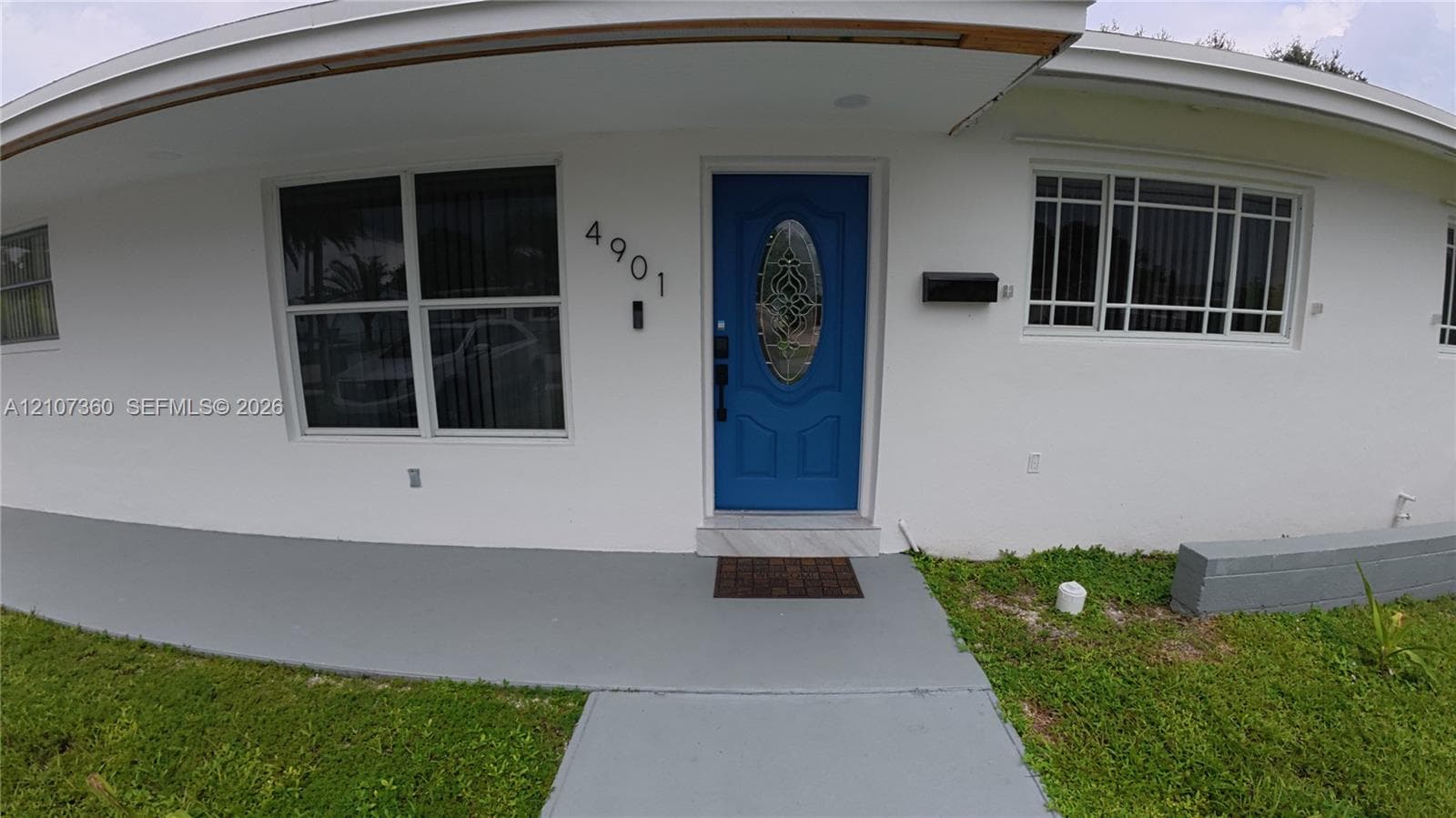 Exterior entry featuring a painted front door with an oval glass insert, multi-pane windows, a covered front porch, and a concrete walkway