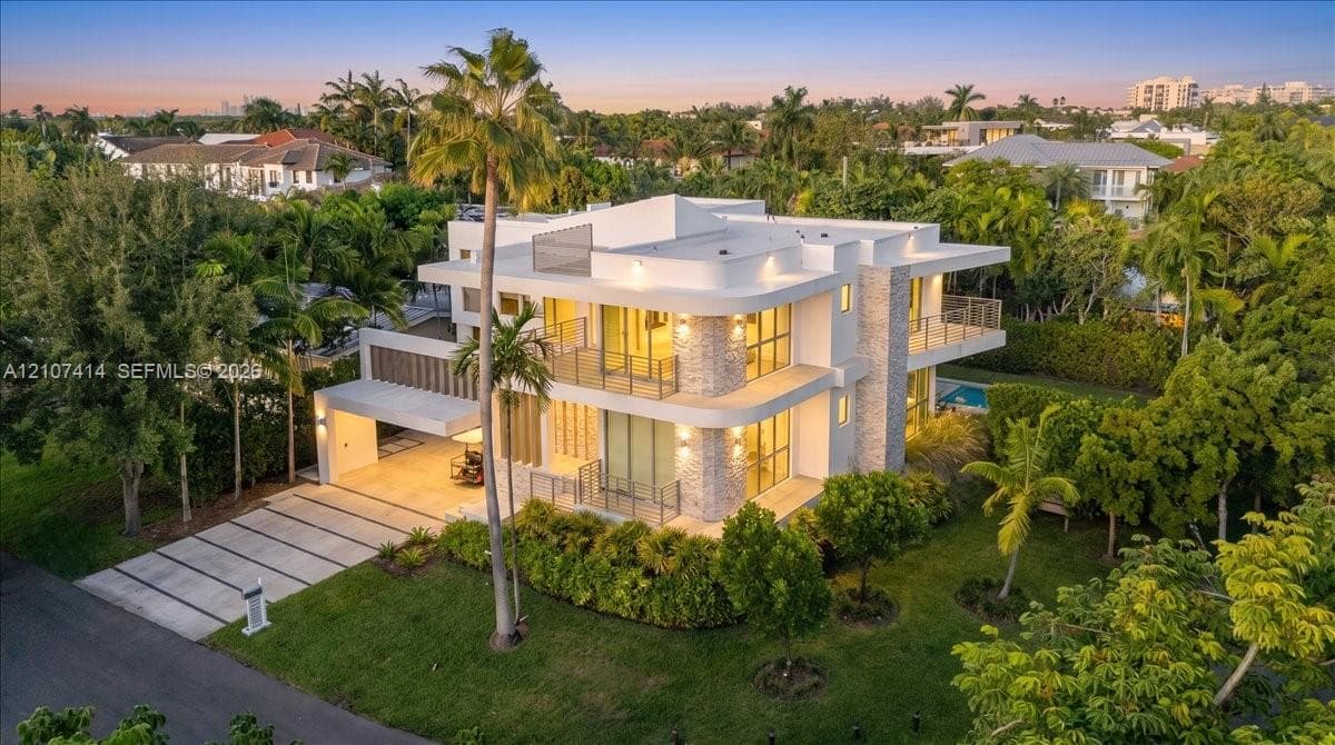 Modern multi-level residence featuring a concrete exterior, stone veneer accents, multi-level balconies with metal railings, and a paved driveway