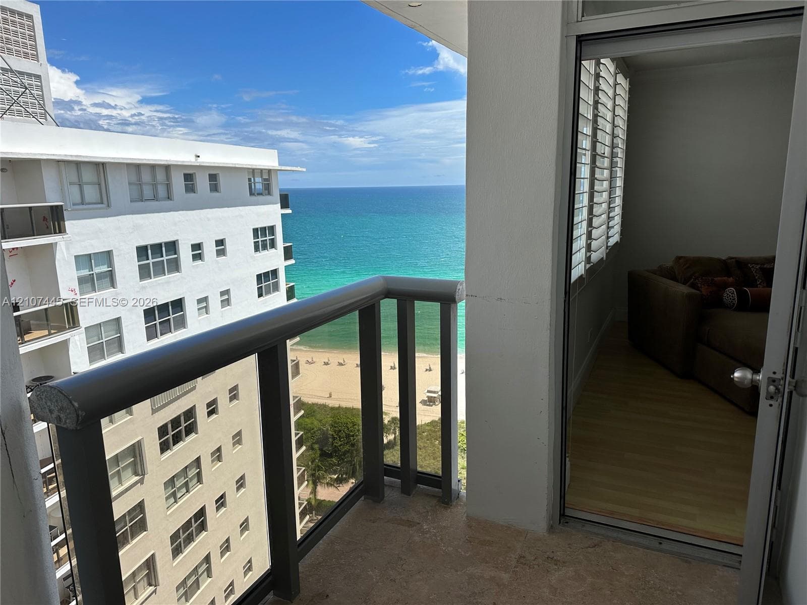 Covered balcony featuring stone flooring and a railing with glass panels, showcasing ocean and coastline scenery