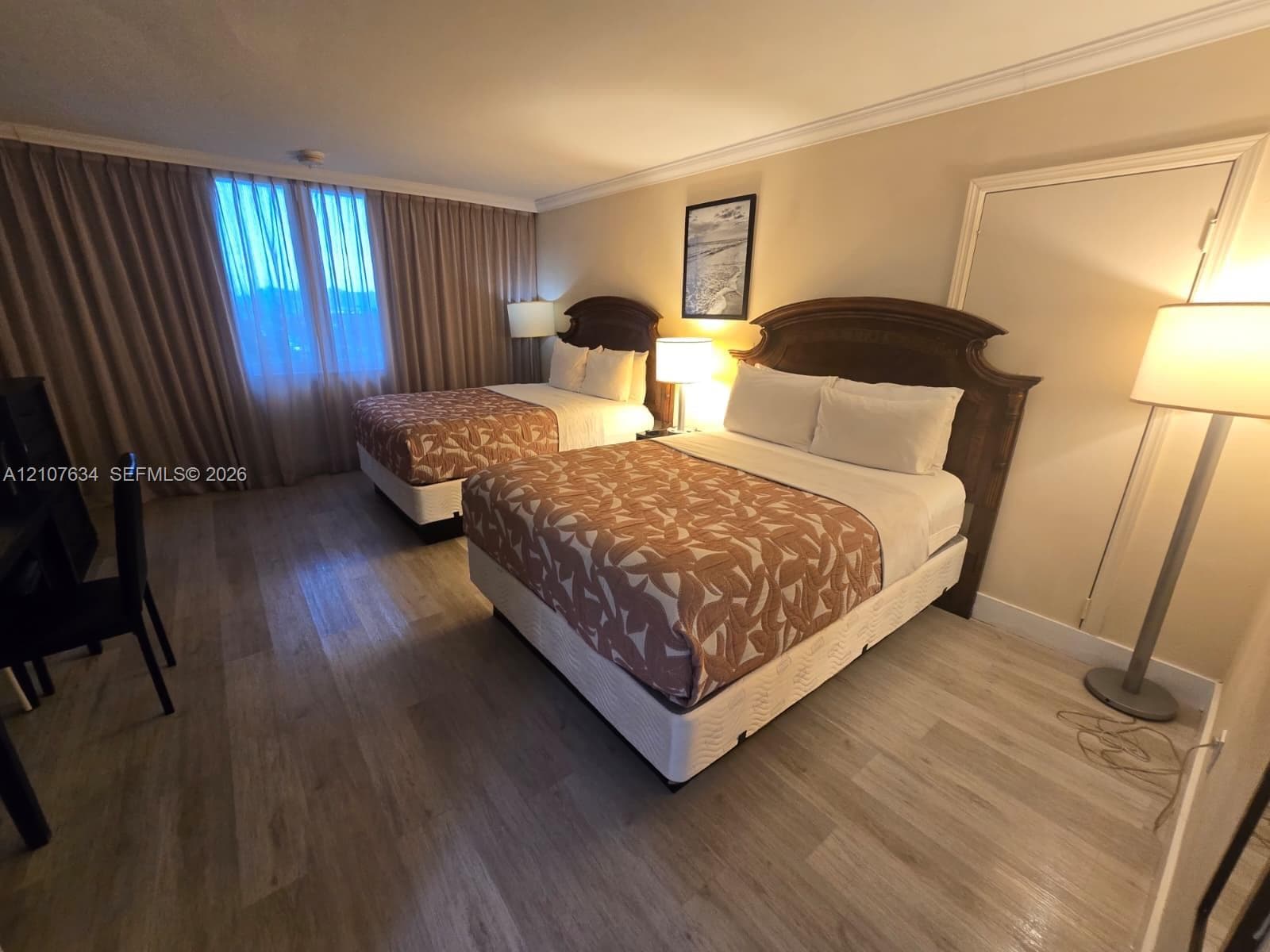 Room featuring wood-finish flooring, full-height window drapery, and crown molding