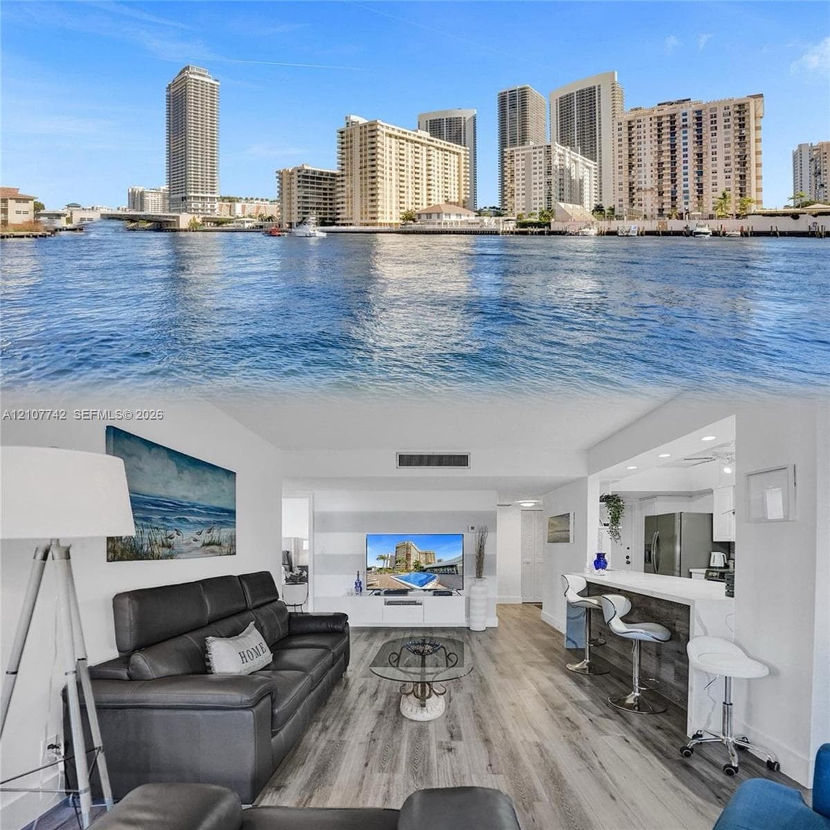 Waterfront living area featuring wood-finish flooring, a breakfast bar with stone-look countertop, and expansive exterior water and city skyline outlooks