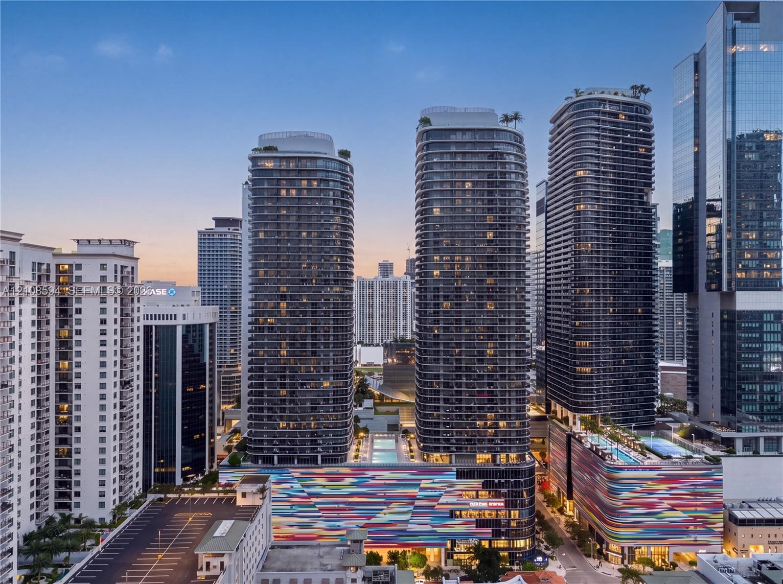 High-rise residential towers featuring floor-to-ceiling glass facades, wrap-around balconies, rooftop landscaping, and integrated multi-level parking structures