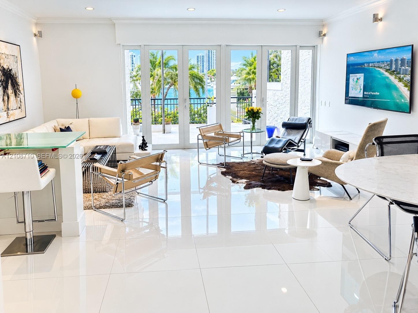 Open-concept living space featuring high-gloss tile flooring, recessed lighting, and multi-panel glass doors with a water-facing exterior