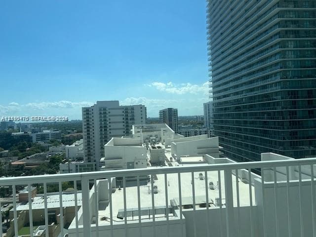 High-rise balcony with white metal railing overlooking an urban cityscape